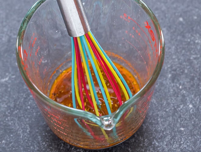 olive oil and lemon dressing in a measuring jar with a wire whisk