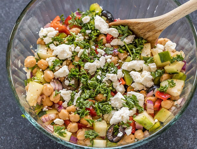 bowl with chickpeas, chopped onion,olives, cucumber, pepper, parsley and feta cheese