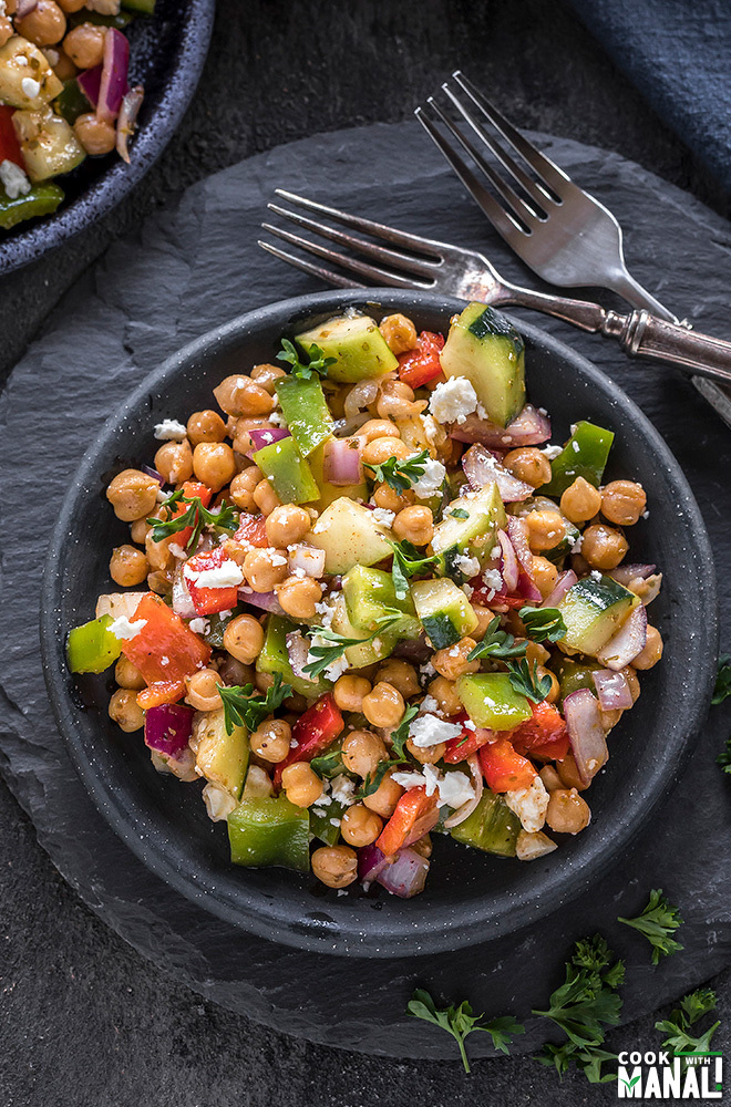 mediterranean chickpea salad in a small black plate with forks on the side