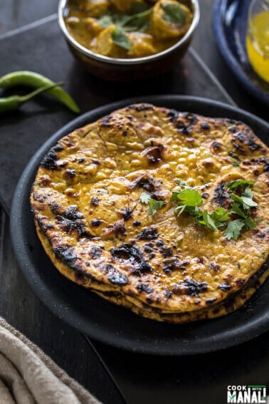 missi roti served in black round plate with green chilies in the background