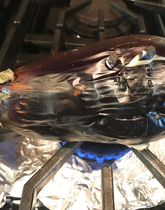 whole eggplant being roasted on heat