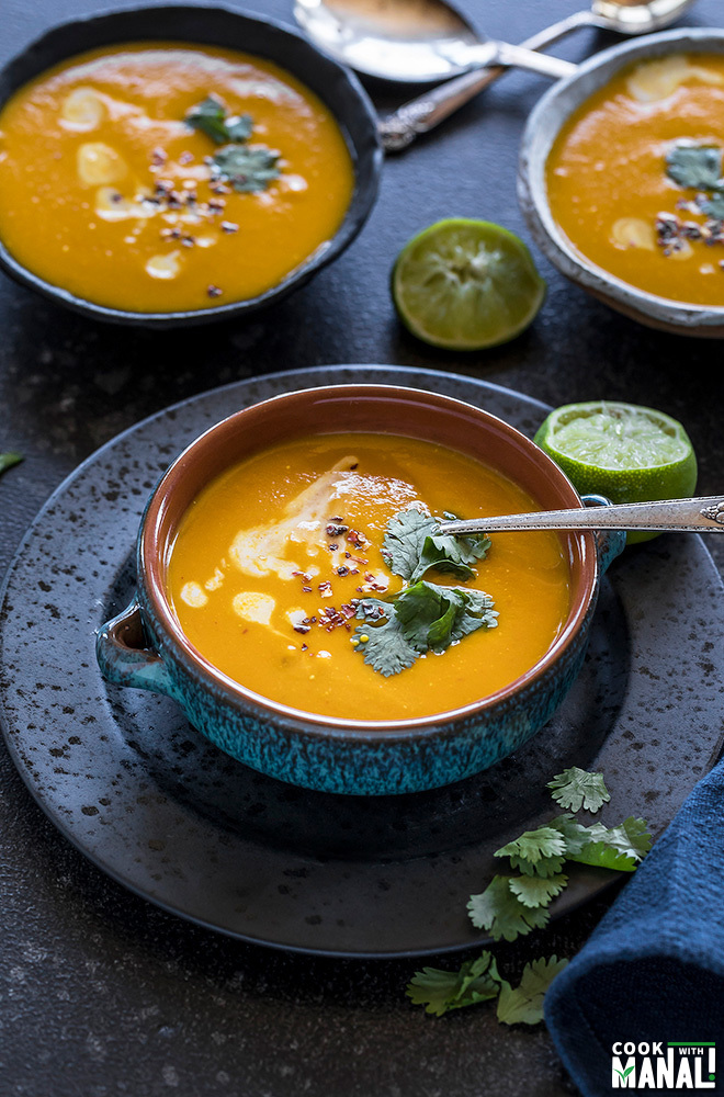 Thai Butternut Squash Soup served in a blue bowl with squeezed lime and cilantro on the side