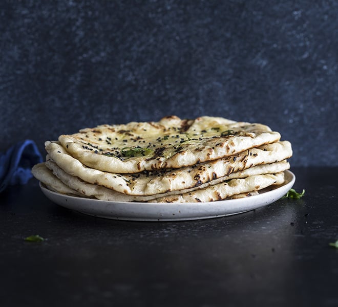 5 pieces of garlic naan stacked together in a plate