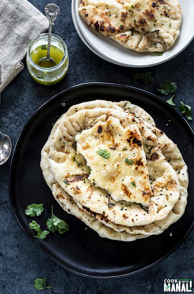 garlic naan stacked in a plate with a plate in the background