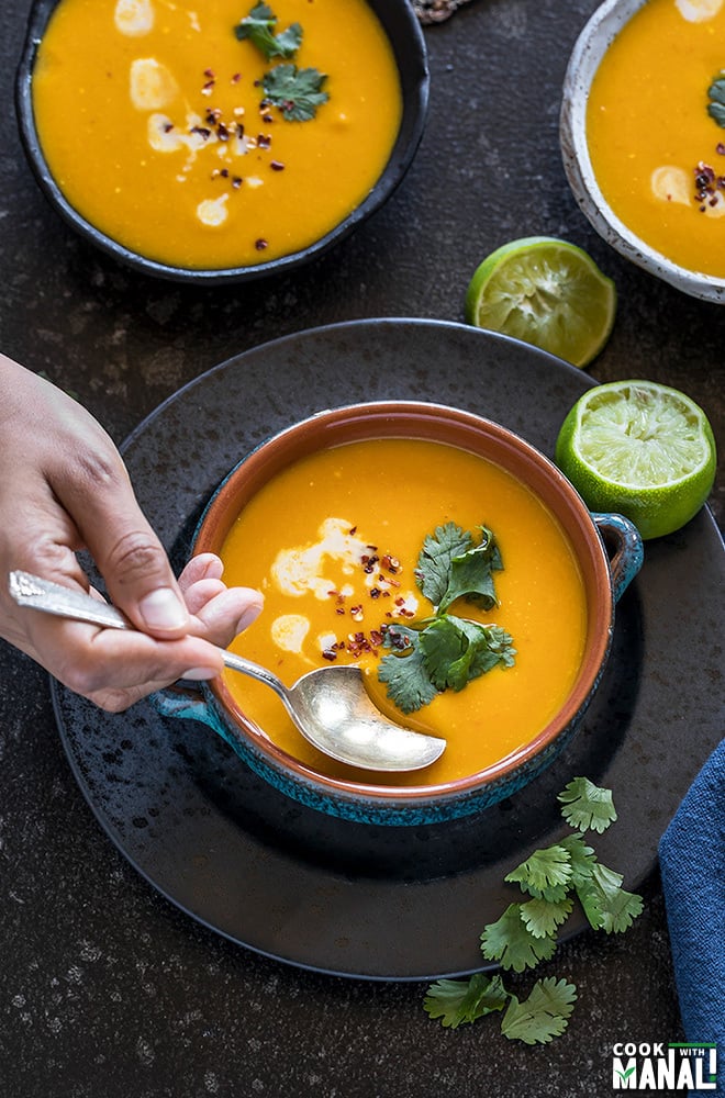 Thai Butternut Squash Soup served in a blue bowl with squeezed lime on the side