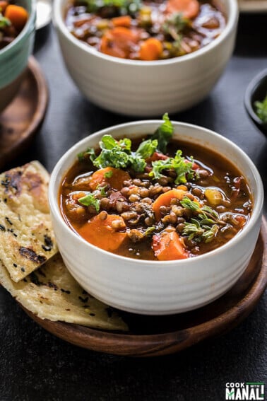 vegan lentil soup in a white bowl with bread on the side