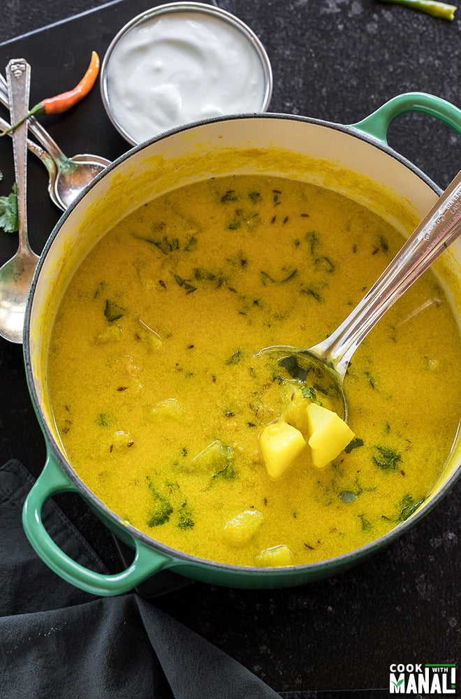 dahi aloo served in a green pot with a ladle