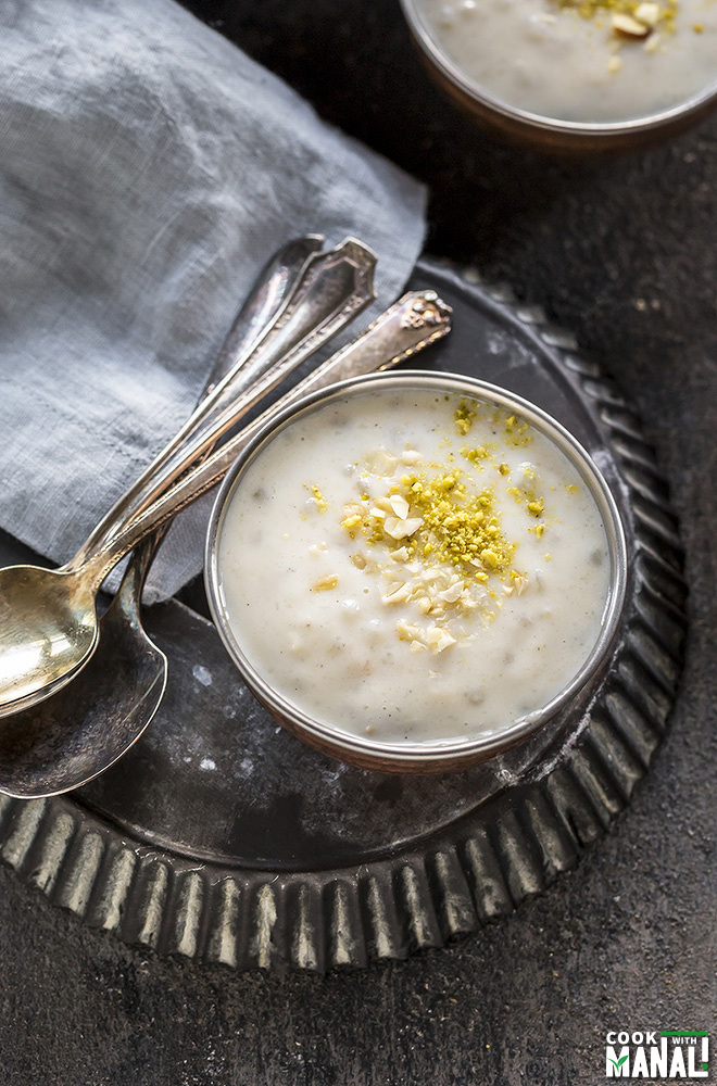 sabudana kheer served in a small copper bowl with stack of spoons behind