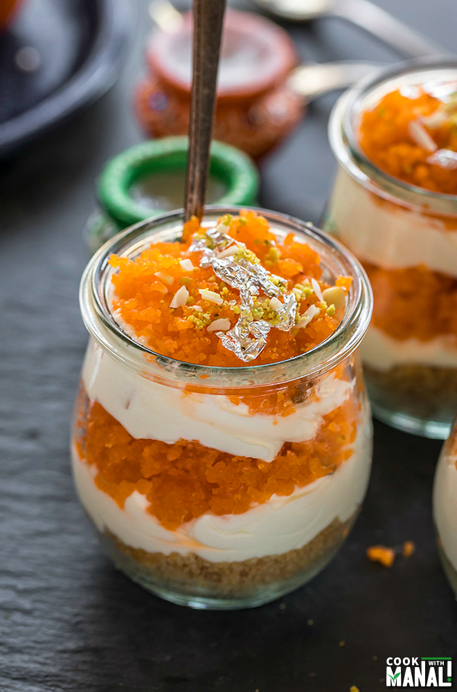jar of motichoor ladoo cheesecake with a spoon inside the jar and diyas in the background