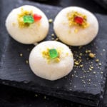 three pieces of sandesh on a black coaster