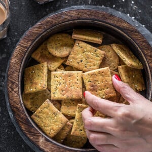 hand picking of a piece of baked methi mathri from a wooden box