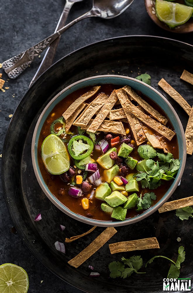 instant pot vegetarian tortilla soup in a bowl topped with tortilla strips, avocado, cilantro, lime wedge and jalapenos