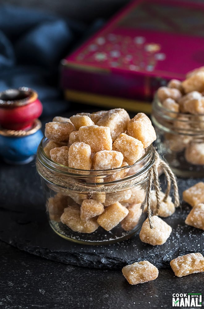 khurma in a glass container wit a sweet box and diyas in the background