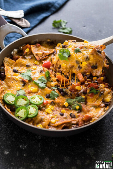 one-pot vegetarian enchiladas in a skillet with a spatula lifting of the cheese