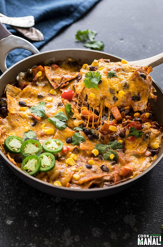 one-pot vegetarian enchiladas in a skillet with a spatula lifting of the cheese