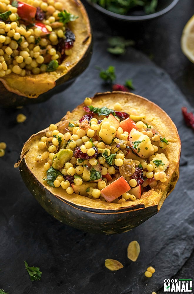 cut acorn squash stuffed with israeli couscous and garnished with fresh herbs