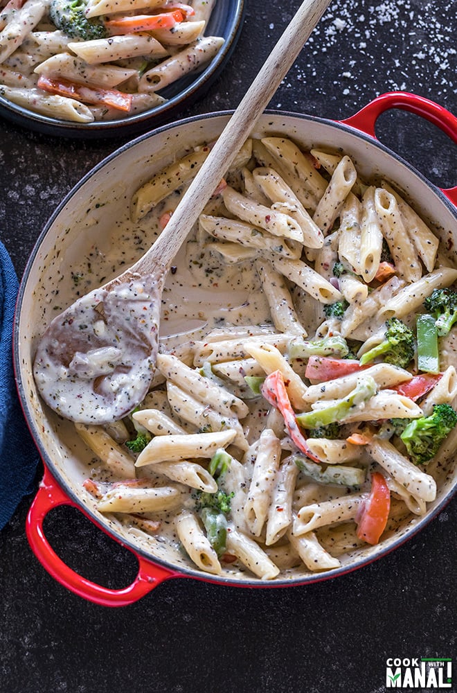 red pot with pasta with veggies in a white sauce