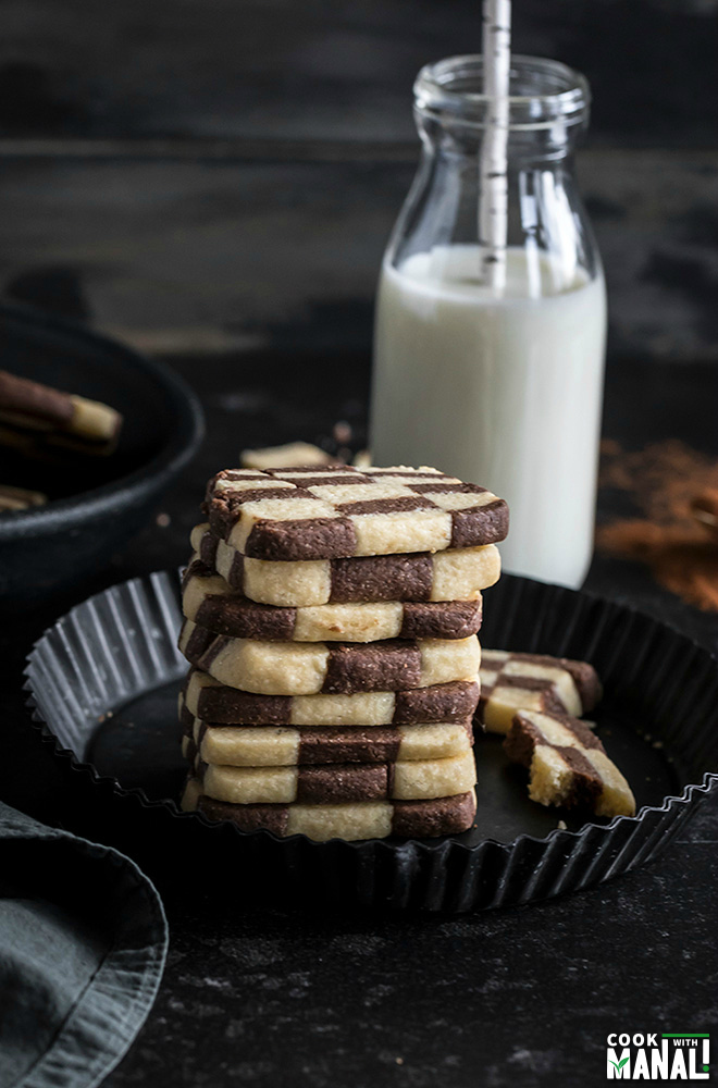 stack of checkerboard cookies with a bottle of milk in the background