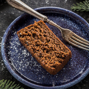 slice of vegan gingerbread cake in a blue plate with a fork on the side
