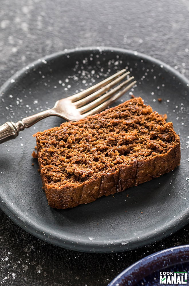 sliced of vegan gingerbread cake in a round black plate with a fork