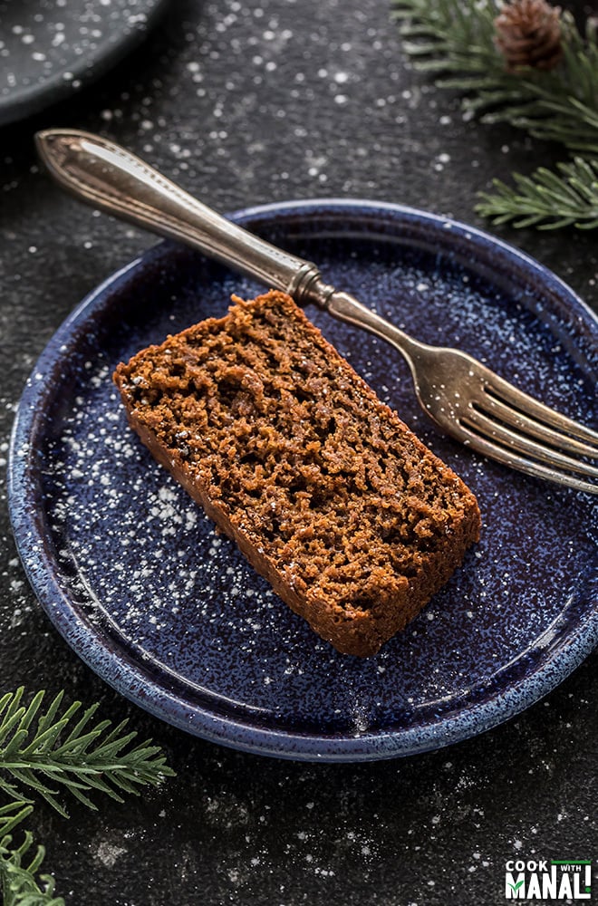 slice of vegan gingerbread cake in a blue plate with a fork on the side