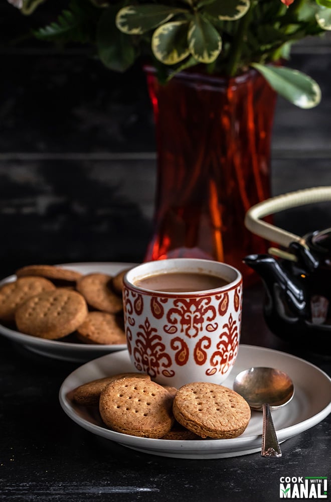 jaggery cookies with a cup of chai on side, teapot in the background