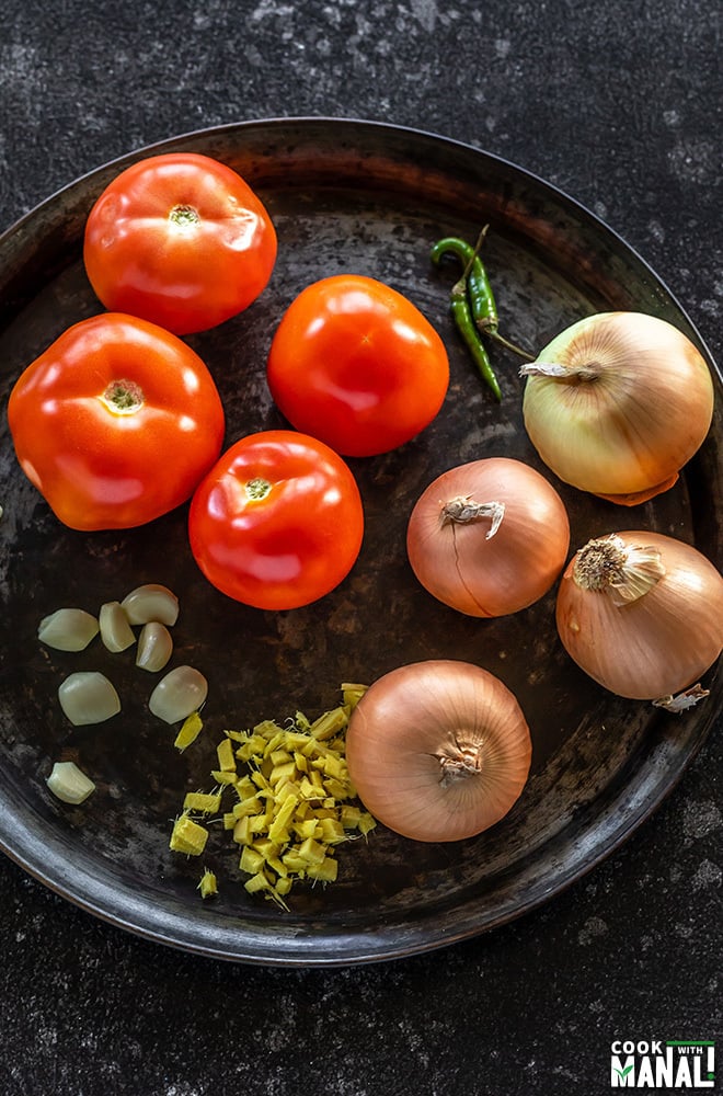 onion, tomato, garlic, ginger and green chilies placed on a round black tray