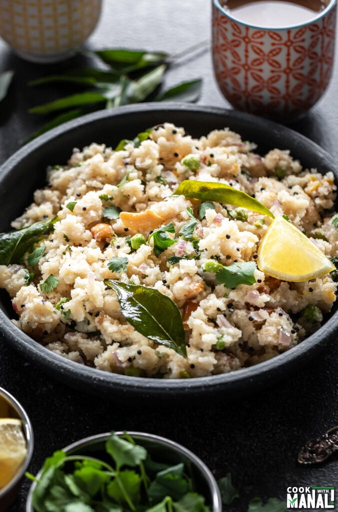 bowl of rava upma with chai and curry leaves in the background