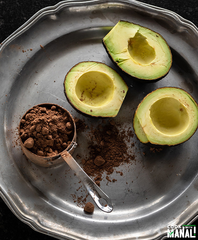 silver plate with cut avocados and cup of cocoa powder