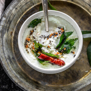 bowl of coconut chutney tempered with curry leaves, mustard seeds, dried red chilies and served with a spoon