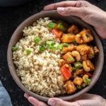 pair of hands holding a bowl of honey cashew tofu