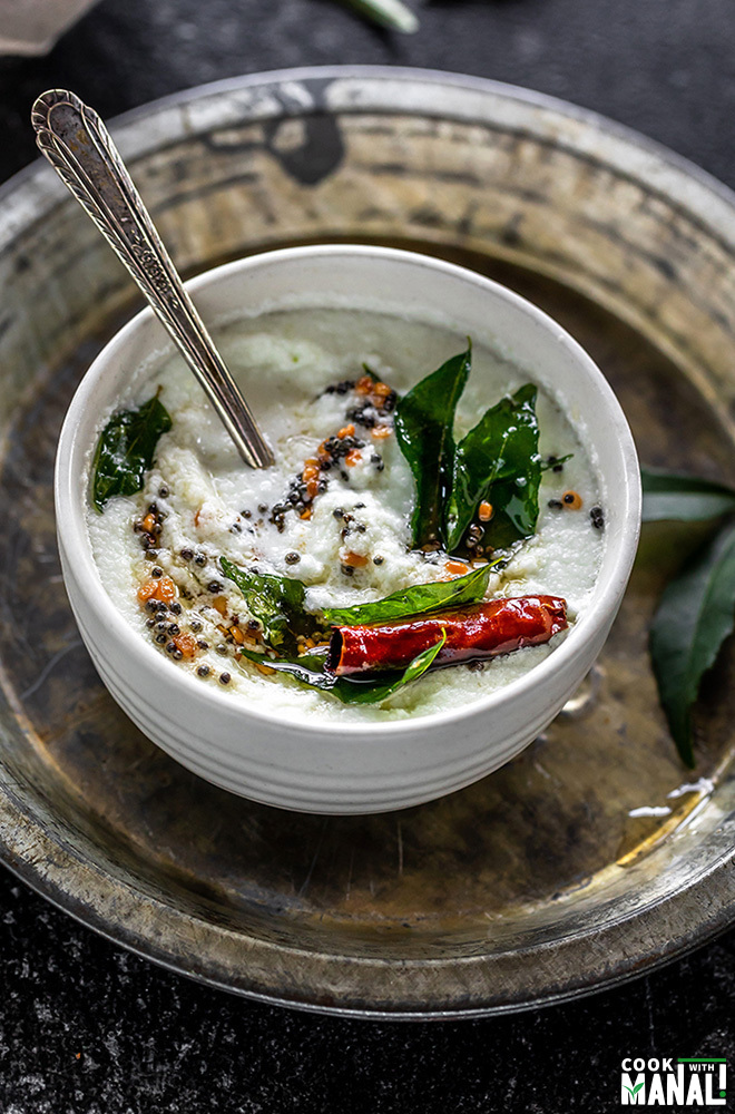 bowl of coconut chutney tempered with curry leaves, mustard seeds, dried red chilies and served with a spoon