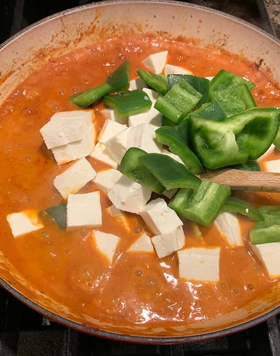 paneer and bell peppers added to a curry