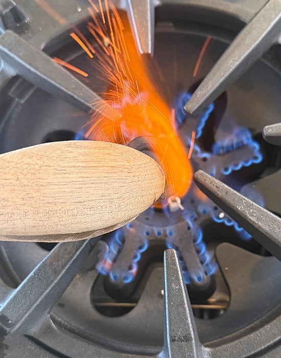 a tong holding a piece of charcoal and burning it in fire