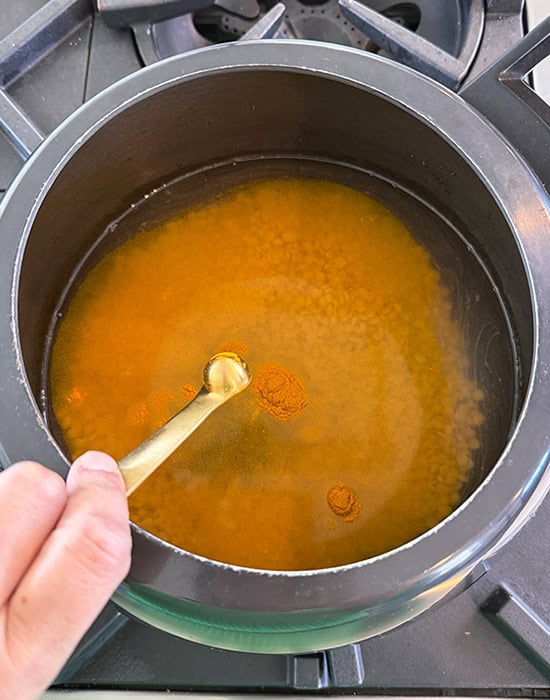 adding turmeric to dal in a pressure cooker