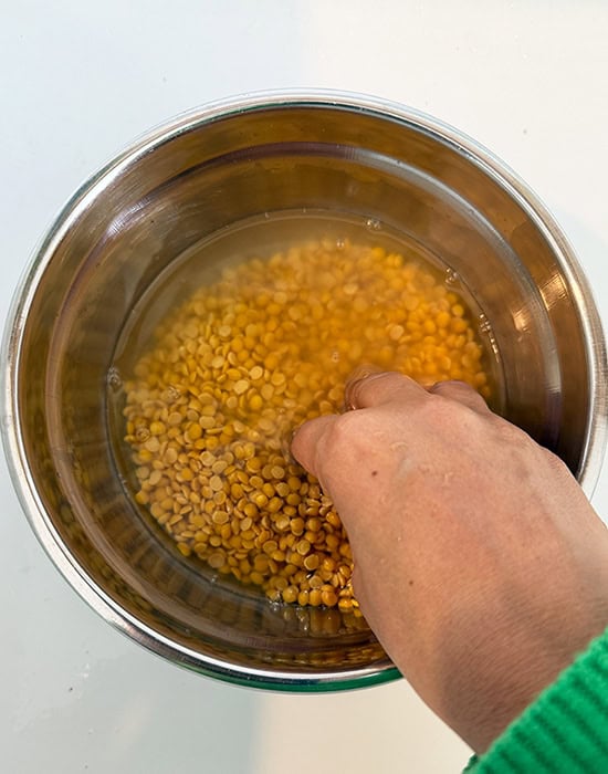 hand rinsing dal in a bowl