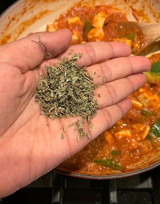 kasuri methi being added to a curry