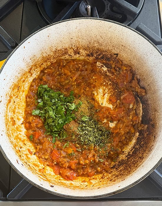 chopped cilantro with onion tomato masala in a pot
