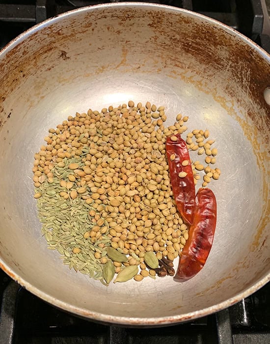 whole spices like coriander seeds, chilies in a kadai