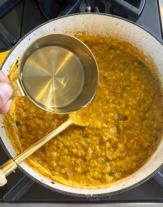 adding water to dal in a pot