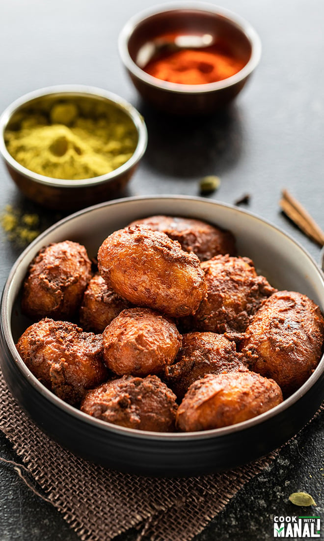 kashmiri dum aloo served in a bowl with small bowls of spices in the background