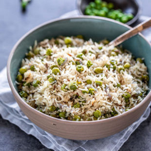 bowl of matar pulao with spoon placed on a blue napkin