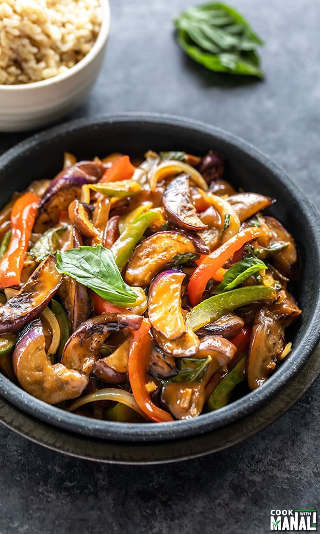 thai basil eggplant served in a black bowl and garnished with fresh basil