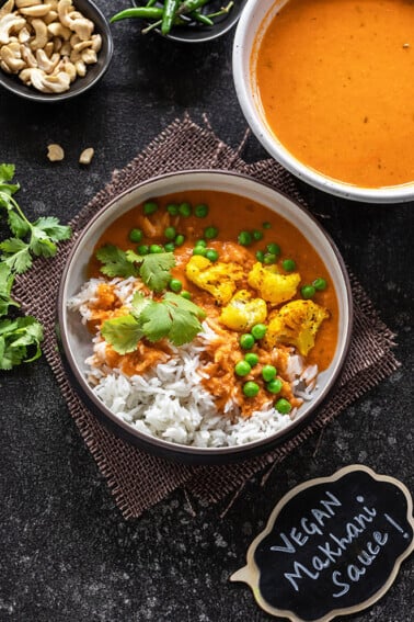 shot of vegan makhani sauce with cauliflower and green peas served over white rice and garnished with cilantro.