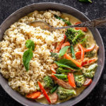 vegan thai green curry served with brown rice in a black bowl