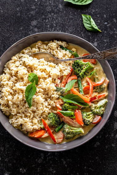 vegan thai green curry served with brown rice in a black bowl