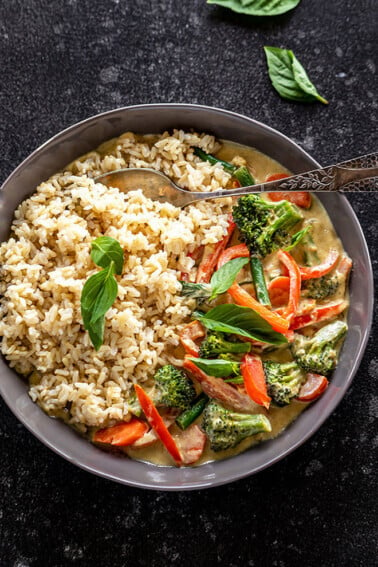 vegan thai green curry served with brown rice in a black bowl