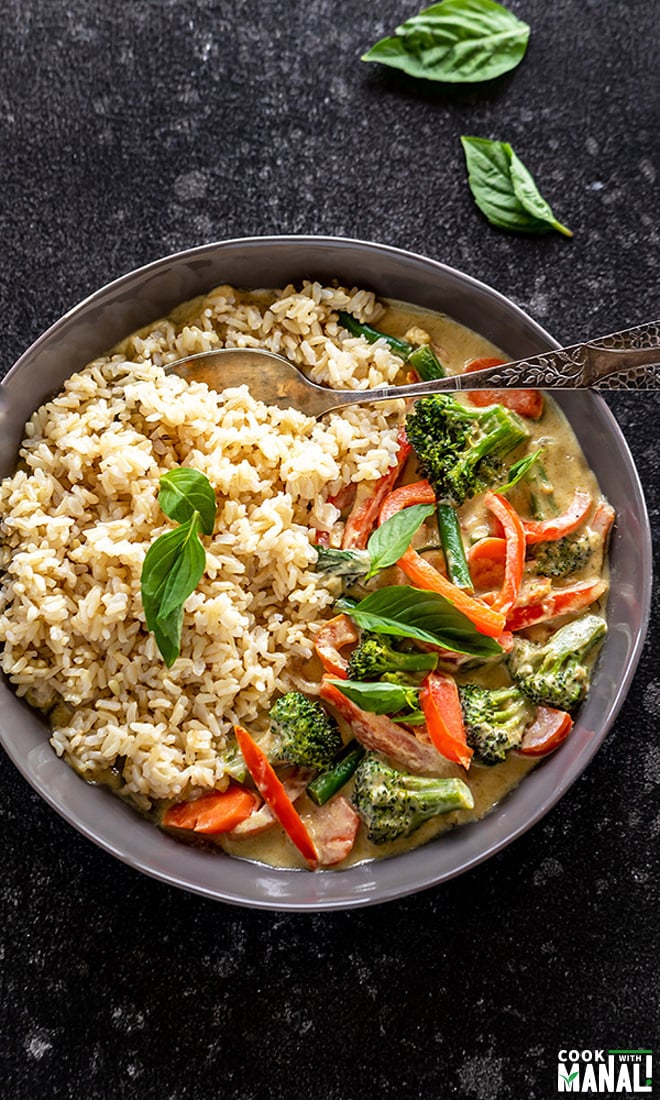 vegan thai green curry served with brown rice in a black bowl