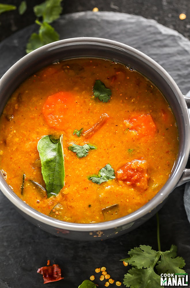 overhead shot of a bowl of sambar garnished with cilantro and curry leaves