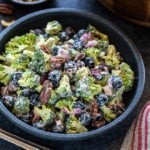 bowl of vegan broccoli salad with blueberries and a fork on the side